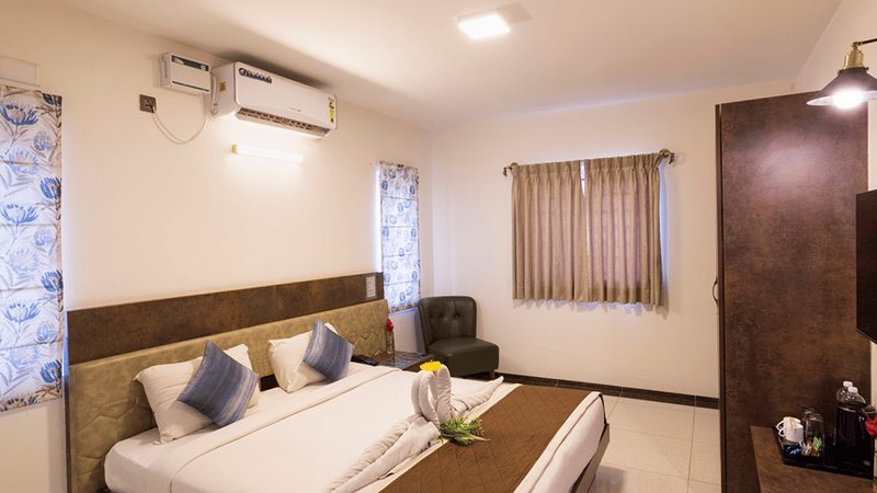 Contemporary bedroom with seating area and air conditioning at Nirantara Resort.