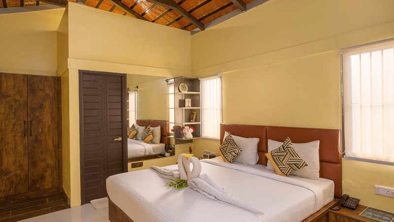 Cosy bedroom with elegant decor and wooden furnishings at Nirantara Resort.