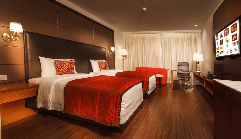 Twin room with two beds, seating area and work desk.